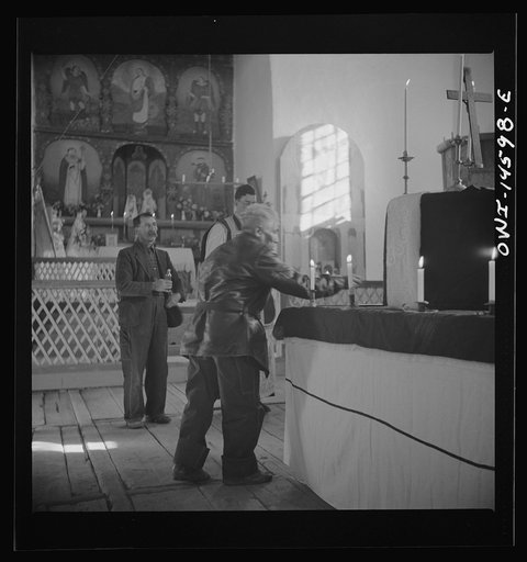 Trampas, New Mexico. Member of the congregation leaving an offering during a memorial mass in church which was built in 1700 and is the best-preserved colonial mission in the Southwest