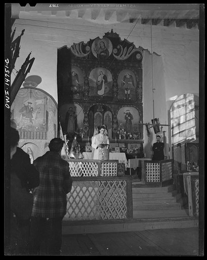 Trampas, New Mexico. Father Cassidy, resident priest of the parish of Penasco, giving a sermon in Spanish. The acolyte of the church is standing at his left
