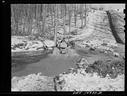 Pennsylvania section of the war emergency twenty-four inch pipeline to carry oil from Texas fields to eastern refineries, completed in July 1943. Caterpillar tractor going through a stream crossed by the pipeline