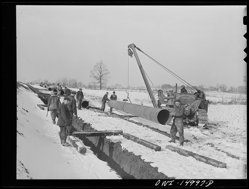 Pennsylvania section of the war emergency twenty-four inch pipeline to carry oil from Texas fields to eastern refineries, completed in July 1943. Moving a forty-foot section of pipe into place where it will be welded to the main line