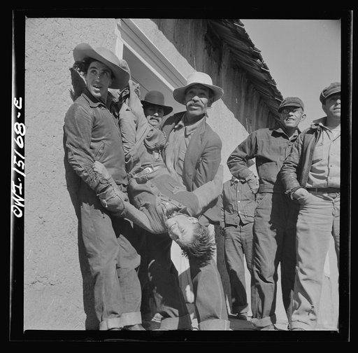 Chacon, Mora County, New Mexico. Idlers at the general store holding a small boy for the photographer