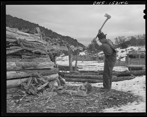 Untitled photo, possibly related to: Trampas, New Mexico. Juan Lopez, the majordomo (mayor) [i.e., steward], cutting and splitting wood for the fireplace and the cook stove