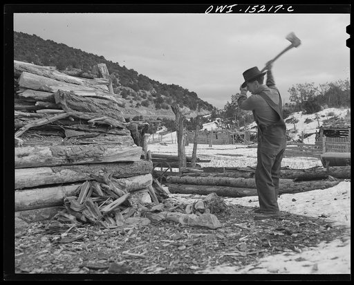 Untitled photo, possibly related to: Trampas, New Mexico. Juan Lopez, the majordomo (mayor) [i.e., steward], cutting and splitting wood for the fireplace and the cook stove