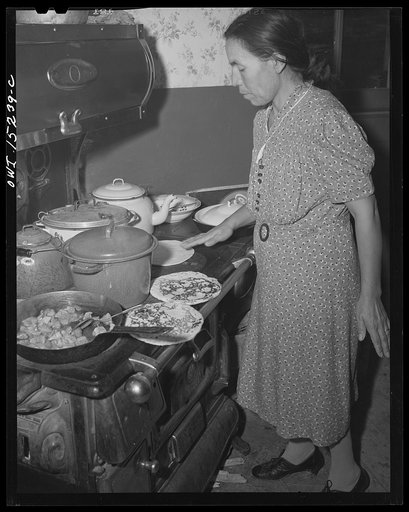 Untitled photo, possibly related to: Trampas, New Mexico. Maclovia Lopez, wife of the majordomo (mayor) [i.e., steward], cooking tortillas directly on the stove