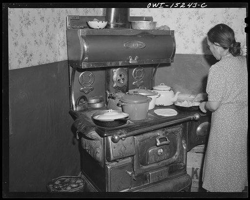 Trampas, New Mexico. Maclovia Lopez, wife of the majordomo (mayor) [i.e., steward], preparing a meal consisting of tortillas, chile, frijoles, potatoes, and possibly home-canned fruit or vegetables