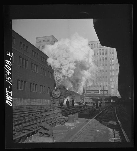 Chicago, Illinois. Double header Pennsylvania railroad train pulling out of Union station. The building in the background is the United States Post Office