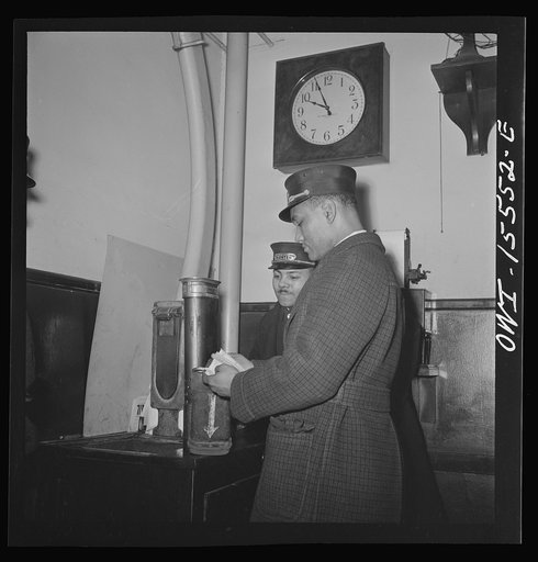 Chicago, Illinois. Pullman porters receiving reservation diagrams for their trains through pneumatic tubes from the reservation room. This is in the passenger agent's room of the Union Station