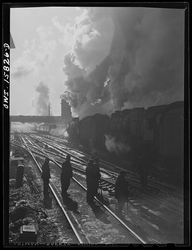 Chicago, Illinois. A double-header pulls out of the Union Station as a section crew watches
