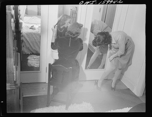 Untitled photo, possibly related to: Detroit, Michigan. Girl putting on lipstick and another girl straightening seams in her stocking