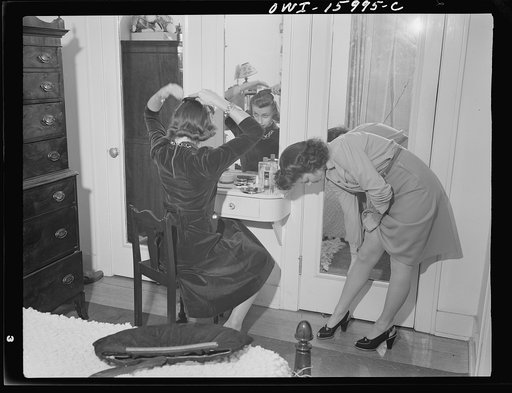 Detroit, Michigan. Girl straightening seams in her stockings and another girl combing her hair in a mirror