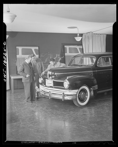 Detroit, Michigan. Norman Bel Geddes and Nash-Kelvinator corporation officials inspecting a marked-up model of a new car