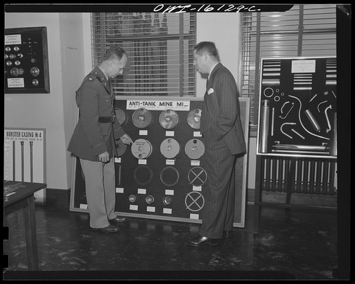 Detroit, Michigan. Conference between U.S. Army ordnance and washing machine industry officials to determine the ability of manufacturers to produce parts needed by the Army. After inspecting samples, blueprints and prices were discussed. Exhibit showing parts of an anti-tank mine