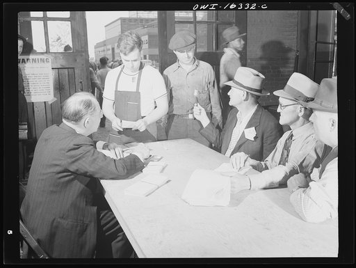 Dearborn, Michigan. National Labor Relations Board election for union representation at the River Rouge Ford plant. Workers receiving a ballot. Government official and labor checkers seated at the table