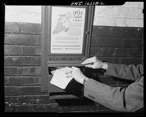 Detroit, Michigan. A box for suggestions from workers installed in the Cadillac motor car division of General Motors Corporation(?). Suggestion box with worker placing suggestions within