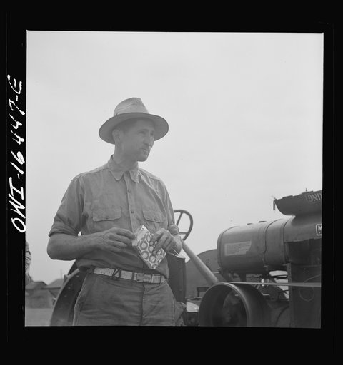 Untitled photo, possibly related to: Jackson, Michigan. Soldier, who was granted a furlough to help with the harvesting on this farm, watching threshing