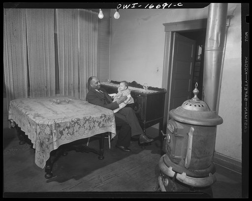Detroit, Michigan. Negro father playing with baby daughter. Old style burner in the foreground. These are conditions under which families originally lived before moving to the Sojourner Truth housing project
