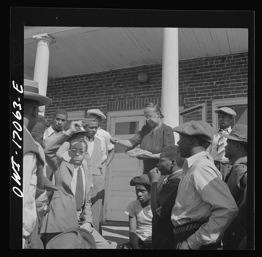 Untitled photo, possibly related to: Daytona Beach, Florida. Bethune-Cookman College. Mrs. Shaw handing out mail to college and NYA (National Youth Administration) students in front of the boys' dormitory