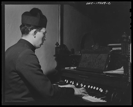 Taos County, New Mexico. Father Cassidy, the Catholic priest of the parish of Penasco, playing the organ