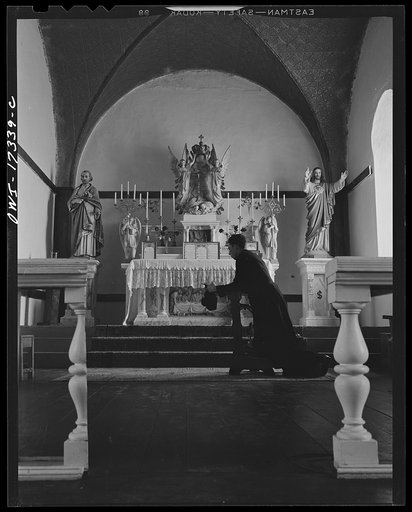 Taos County, New Mexico. Father Cassidy, the Catholic priest of the parish of Penasco, kneeling before the altar