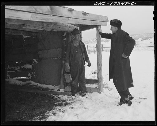 Taos County, New Mexico. Father Cassidy, the Catholic priest of the parish of Penasco, looking at the animal shelter on the farm of a parishioner who has asked for his advice