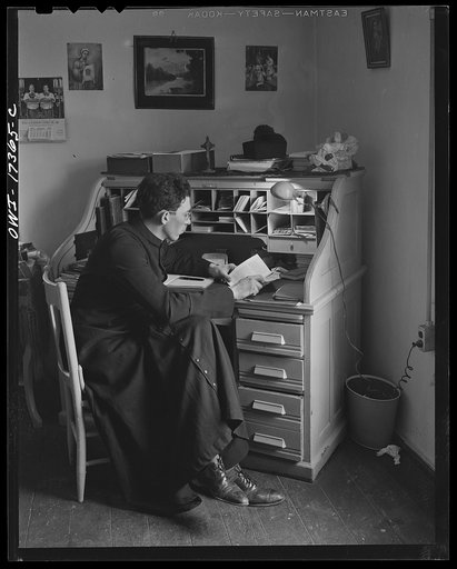 Taos County, New Mexico. Father Cassidy, the Catholic priest of the parish of Penasco, at his desk