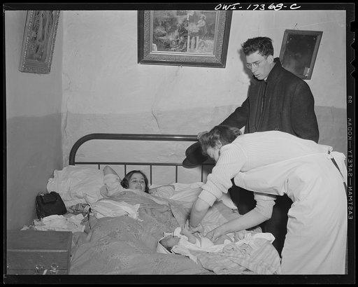 Taos County, New Mexico. Father Cassidy, the Catholic priest of the parish of Penasco, visiting a mother and her new baby. He cooperates with the public health nurse in establishing a health education program among his parishioners