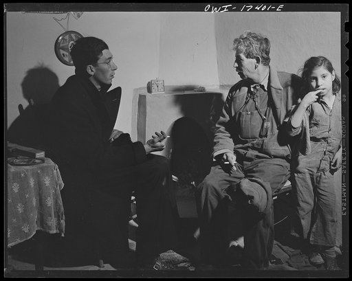 Taos County, New Mexico. Father Cassidy, the Catholic priest of Penasco, smoking and talking things over with a parishoner