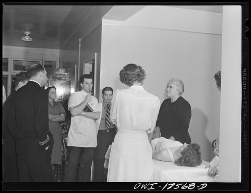 Untitled photo, possibly related to: Minneapolis, Minnesota. Sister Kenny conducting a class for doctors and nurses at the Elizabeth Kenny Institute. The two men in uniform are medical officers of the United States Coast Guard who came to the institute to see a patient and stay for the class