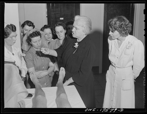 Untitled photo, possibly related to: Minneapolis, Minnesota. Sister Kenny conducting a class for doctors and nurses at the Elizabeth Kenny Institute. The two men in uniform are medical officers of the United States Coast Guard who came to the institute to see a patient and stay for the class