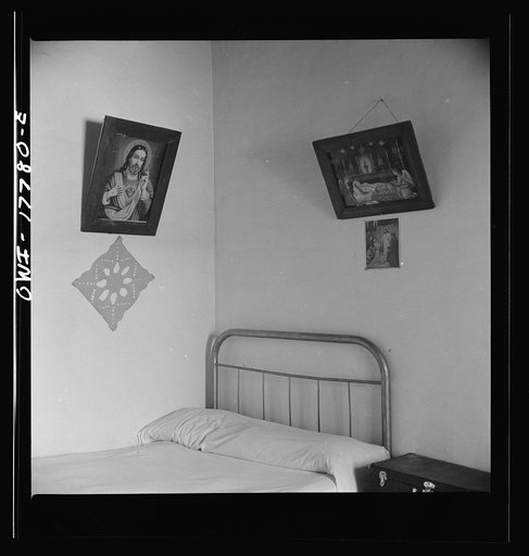 Trampas, New Mexico. In the home of Juan Lopez, majordomo (mayor) [i.e., steward]. Years ago, ancient hand-curved and painted santos hung on the walls in place of these cheap religious prints. Collectors have bought up almost all native art