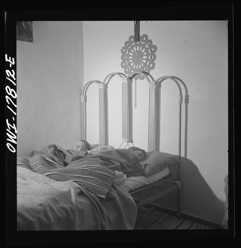 Trampas, New Mexico. In many Spanish-American homes, mattresses are rolled out on the floor at night. But by putting three under a blanket the Lopez family all sleep in beds