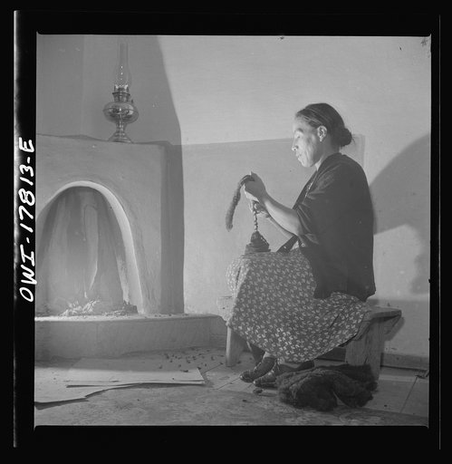 Trampas, New Mexico. Maclovia Lopez, wife of the majordomo (mayor) [i.e., steward], spinning wool by the light of the fire. The family has ten sheep and they spin the wool for blankets, which are woven for them in Cordova