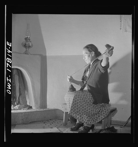 Trampas, New Mexico. Maclovia Lopez, wife of the majordomo (mayor) [i.e., steward], spinning wool by the light of the fire. The family has ten sheep and they spin the wool for blankets, which are woven for them in Cordova