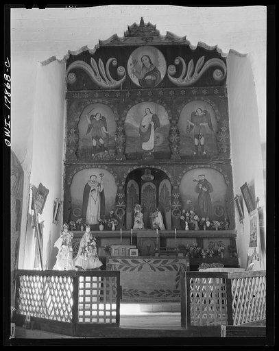 Trampas, New Mexico. Main altar of painted wood in a church which was built in 1700, and is the best-preserved colonial mission in the Southwest. There is an older altar behind the wooden one which is painted directly on the adobe wall