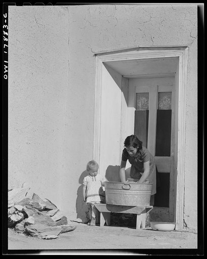 Trampas, New Mexico. One of the daughters of Juan Lopez, majordomo [i.e., steward], doing the family washing. In summer, water is heated out of doors on an open fire, but in winter it is heated in the kitchen on the stove