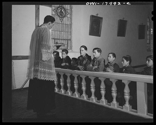 Untitled photo, possibly related to: Taos County, New Mexico. Father Cassidy, the Catholic priest of the parish of Penasco, blessing the merit badges of his troop of Boy Scouts