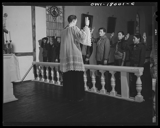 Taos County, New Mexico. Father Cassidy, the Catholic priest of the parish of Penasco, blessing the merit badges of his troop of Boy Scouts