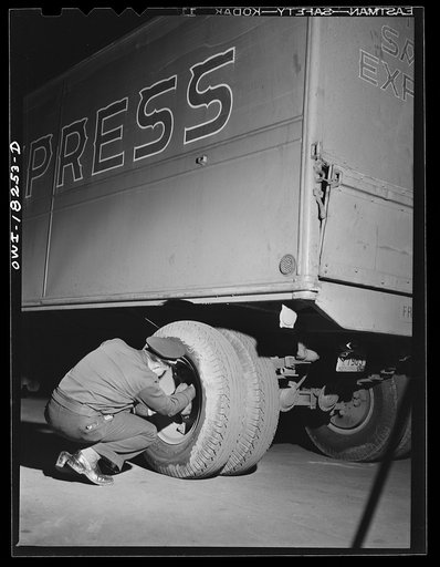Driver checking tires outside a diner where he has stopped for dinner along U.S. Highway 40 in Delaware