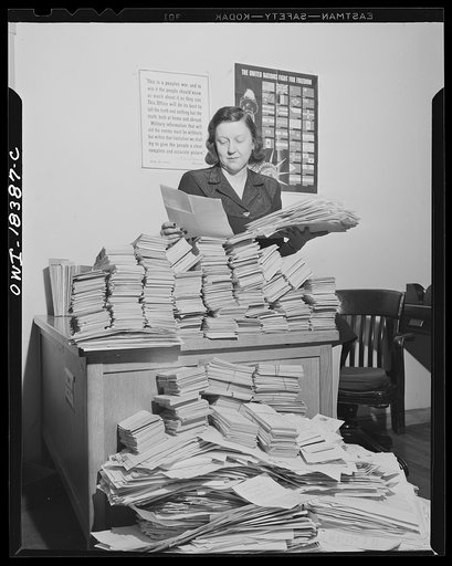Washington, D.C. Government worker reading requests for Office of War Information (OWI) publication "Tale of a city" at the United States Information Center