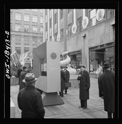 New York, New York. "United Nations" exhibition of photographs presented by the United States Office of War Information (OWI) on Rockefeller Plaza. Listening to broadcasts of President Roosevelt, Churchill, Stalin, and Chiang Kai-Chek, heard every half-hour from a loudspeaker at one end of the frame