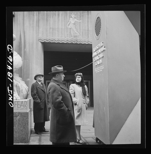 New York, New York. "United Nations" exhibition of photographs presented by the United States Office of War Information (OWI) on Rockefeller Plaza. Listening to broadcasts of President Roosevelt, Churchill, Stalin, and Chiang Kai-Chek, heard every half-hour from a loudspeaker at one end of the frame