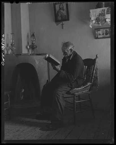 Untitled photo, possibly related to: Trampas, Taos County, New Mexico. Grandfather Romero, the oldest man in the town, is ninety-nine years old (seated in room, reading)