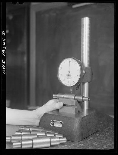 New York, New York. Class in the use of precision instruments, part of the government-sponsored industrial training program at New York University. Most of the students are women. Testing diameter variations and concentricity of ground stepped shafts with a comparator. The readings are in 10,000ths 