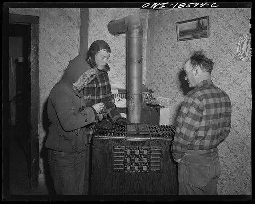 Moreno Valley, Colfax County, New Mexico. George Mutz with his son and oldest daughter, "warming up" before starting their morning chores