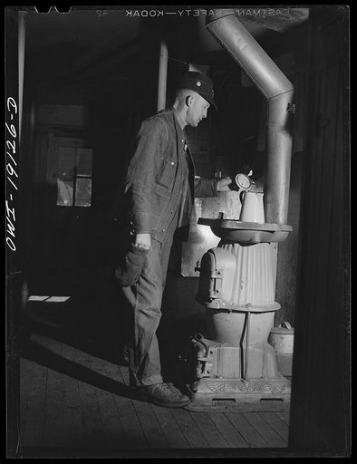 Conductor George E. Burton heats some coffee on the stove in the caboose on the Atchison, Topeka and Santa Fe Railroad enroute to Chillicothe, Illinois