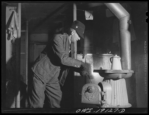 Conductor George E. Burton building a fire in the stove of the caboose on the Atchison, Topeka and Santa Fe Railroad enroute to Chillicothe, Illinois