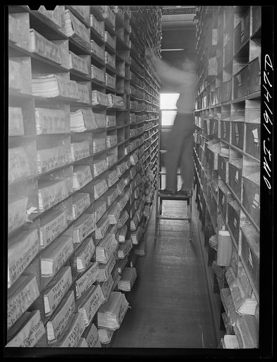 Untitled photo, possibly related to: Kansas City, Missouri. E. A. Schenck, teletype operator, looking up one of the files in the record room of the freight depot