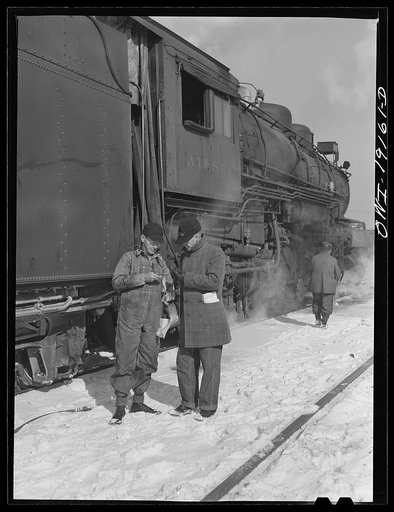 Chicago, Illinois. Atchison, Topeka and Santa Fe Railroad conductor George E. Burton and engineer J.W. Edwards comparing time before pulling out of Corwith Railroad yard for Chillicothe, Illinois