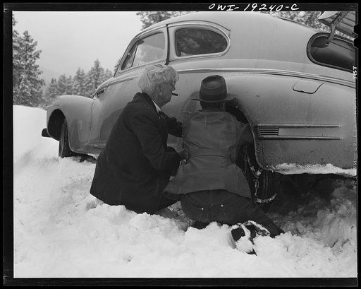 Penasco, New Mexico. Doctor Onstine, seventy-seven year old country physician, putting chains on his car to get from Taos to the clinic operated by the Taos County cooperative health association