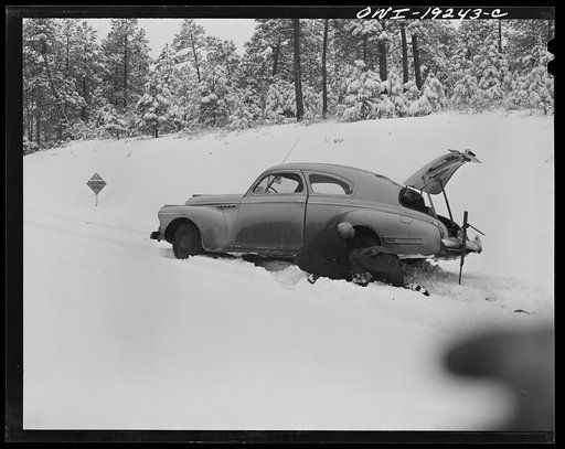 Penasco, New Mexico. Doctor Onstine, seventy-seven year old country physician, putting chains on his car to get from Taos to the clinic operated by the Taos County cooperative health association